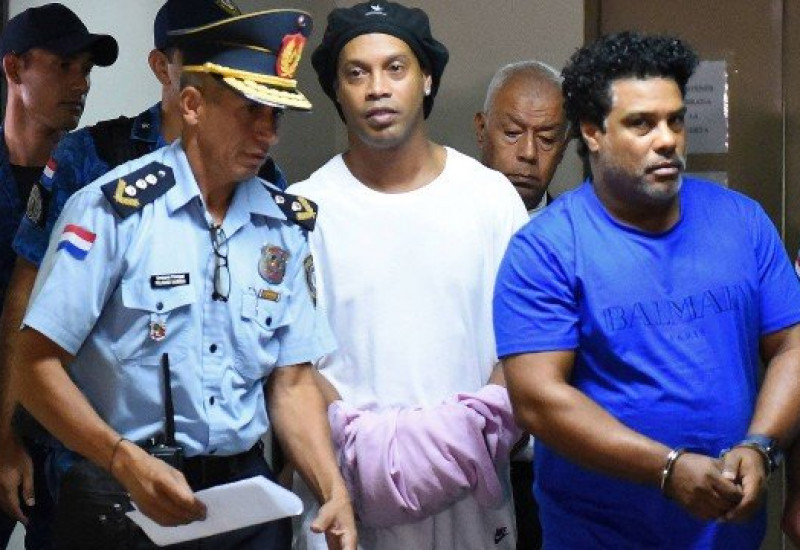 Ronaldinho Gaúcho e o irmão, Roberto Assis, sendo levados algemados para prisão Foto: NORBERTO DUARTE / AFP